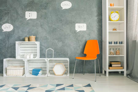 Room with orange chair, crate furniture and white regaleの写真素材