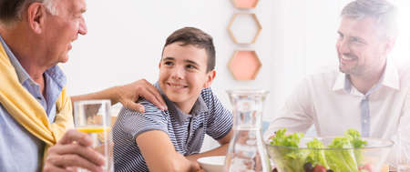 Multigenerational men in family eating dinner at home together