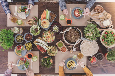 People eating healthy lunch, sitting beside rustic tableの写真素材