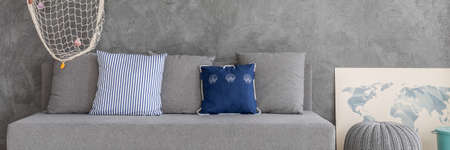 Big and grey couch with grey and blue pillowsの写真素材
