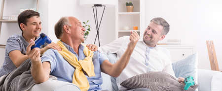 Happy grandfather as a winner in video games with son and grandsonの写真素材