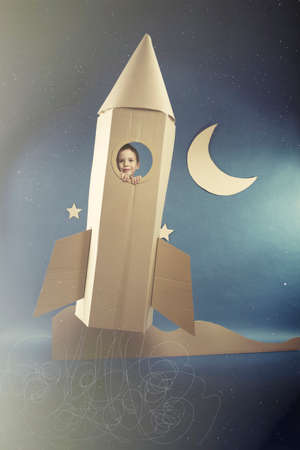 Boy enjoying the spaceflight in paper rocketの写真素材