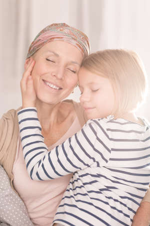 Child hugging ill mother suffering from cancerの写真素材