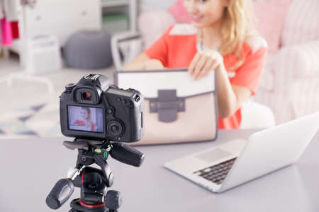 Fashion blogger with woman's bag and laptop filming her video