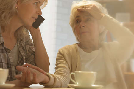 Woman calling help for her ill senior motherの写真素材