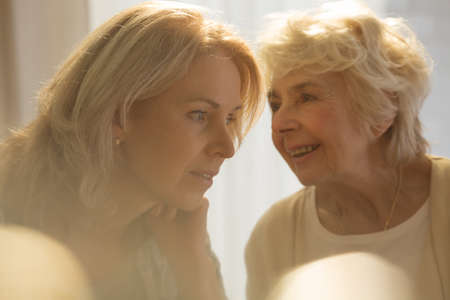 Happy senior woman talking with her caring daughterの写真素材