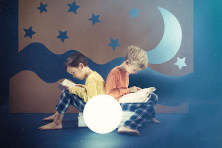 Friends preoccupied by reading books at nightの写真素材