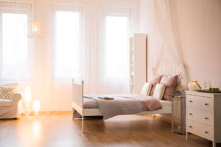 Room with decorative lighting, bed, dresser and sofaの写真素材