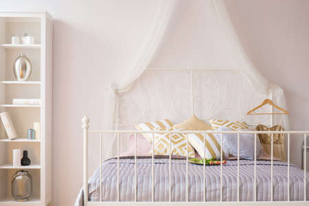 Room with bed with metal headboard and white bookcaseの写真素材