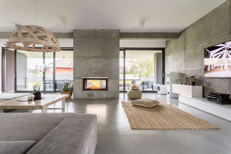 Spacious villa interior with cement wall effect, fireplace and tv