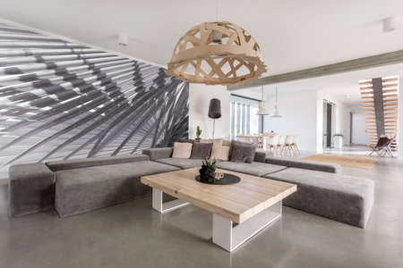 Room with extra large sofa, wooden table and photo wallpaperの写真素材