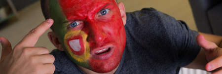 Shot of angry man's face painted in national Portugal colour