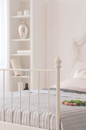 Bed with metal footboard and white bookcaseの写真素材