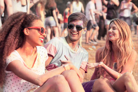 Happy friends with colored clothes and faces relaxing outdoorsの写真素材