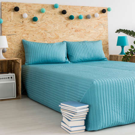 Interior with large bed with a blue counterpane and blue decorationsの写真素材