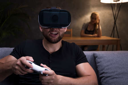Shot of a young man playing games on a sofa and his angry girlfriend sitting beside him