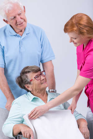 Young caregiver helping elderly woman on wheelchairの写真素材