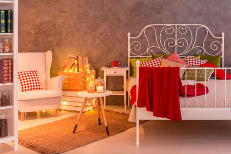 Bedroom with decorative light, bookcase, armchair and bedの写真素材