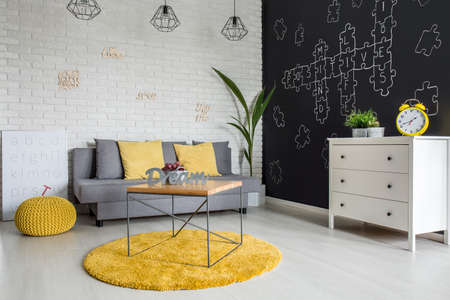 Room with sofa, dresser, blackboard wall and yellow detailsの写真素材