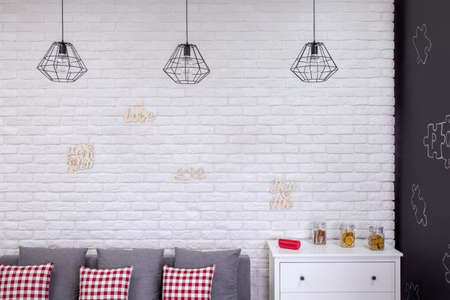 Living room with industrial lamps, sofa, brick wall and dresserの写真素材