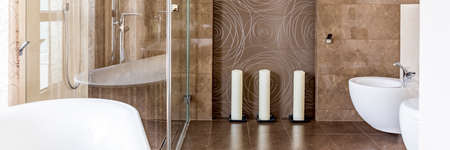 Bathroom with brown tiling, toilet and walk in showerの写真素材