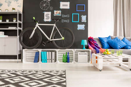 Black and white student room with bicycle, blackboard and sofaの写真素材