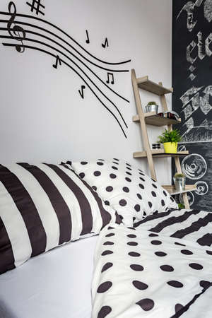 Trendy bedroom with double bed, monochrome patterned sheet and musical accents