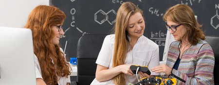 Female scientists in lab coats using modern biotechnology robots