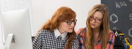 Young female students in glasses analyzing chemistry study during lessonの写真素材