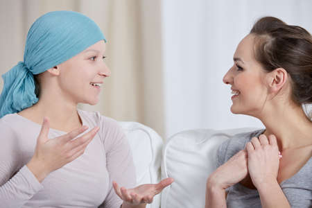 Young cancer woman wearing headscarf, talking with friendの写真素材
