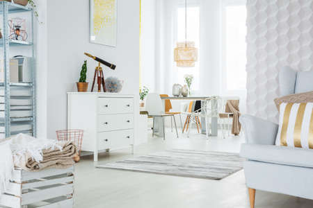White, functional apartment with dresser, armchair and dining area
