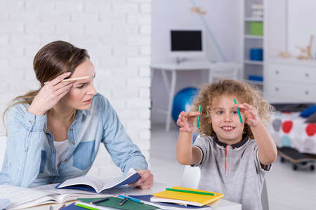 Impatient mother doing homework with distracted son