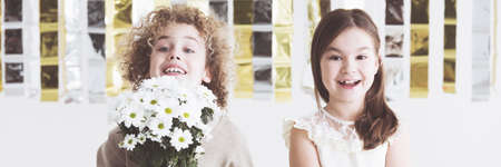 Smiled kids couple with boy keepig flowersの写真素材