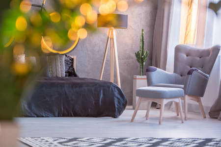 Grey bedroom with black bed, armchair and footstoolの写真素材