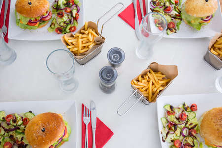 Delicious burgers and fries at table during meal