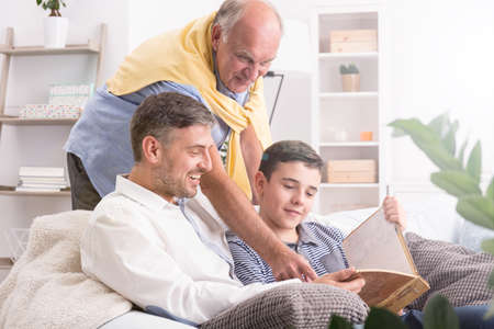 Grandfather watching photos with his son and grandson