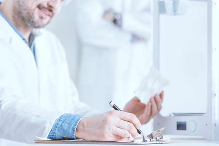 Man wearing white uniform, holding 3d printed modelの写真素材