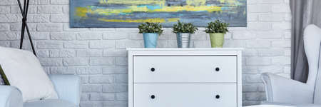 White commode with plants by white brick wallの写真素材