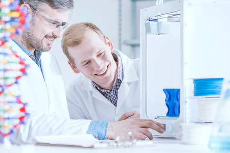 Happy scientist working at laboratory, printing 3d model