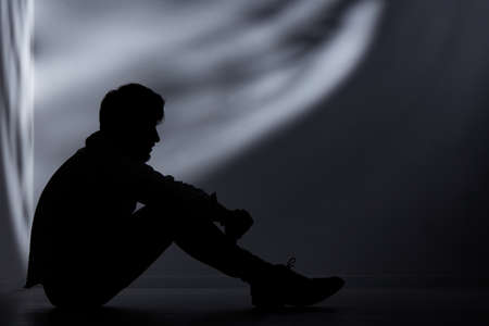 Abandoned man sitting on floor in dark room