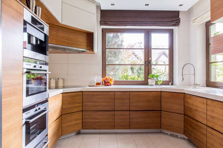 Wooden cupboards and white worktops in new kitchenの写真素材