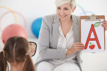Girl during speech therapy with child pedagogueの写真素材
