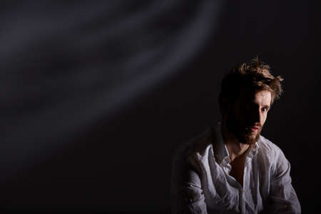 Handsome, young man after nervous breakdown, dark background