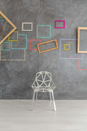 Design modern chair in front of concrete wall with colorful framesの写真素材