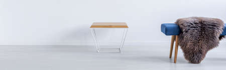 Modern table and blue bench with fur against white wallの写真素材