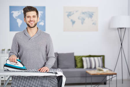 Happy, young man doing houseworks, ironing clothesの写真素材