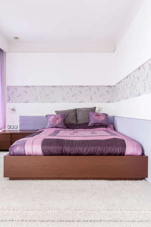 Comfortable double bed in designed purple bedroomの写真素材