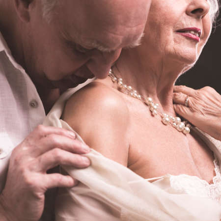 Elderly man kissing his stylish lover's arm with tendernessの写真素材