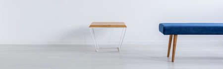 Small table and blue bench in white room