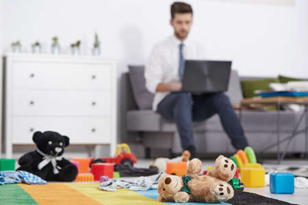 Businessman father with laptop working in messy room